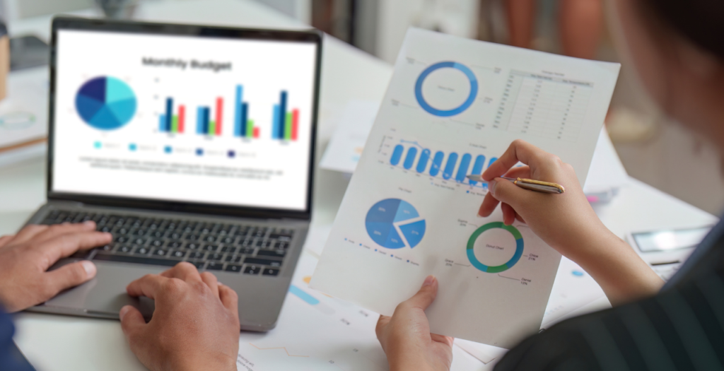 Medical practice financial management represented by a person holding a financial graphic and someone with a different graphic pulled up on a notebook computer