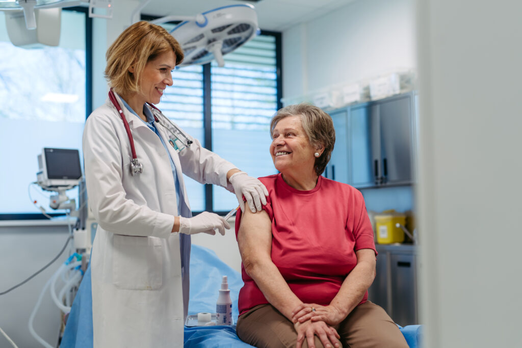 Elderly patient being vaccinated by provider to show Elderly patient being vaccinated by provider in clinic that meets rural health clinic requirements