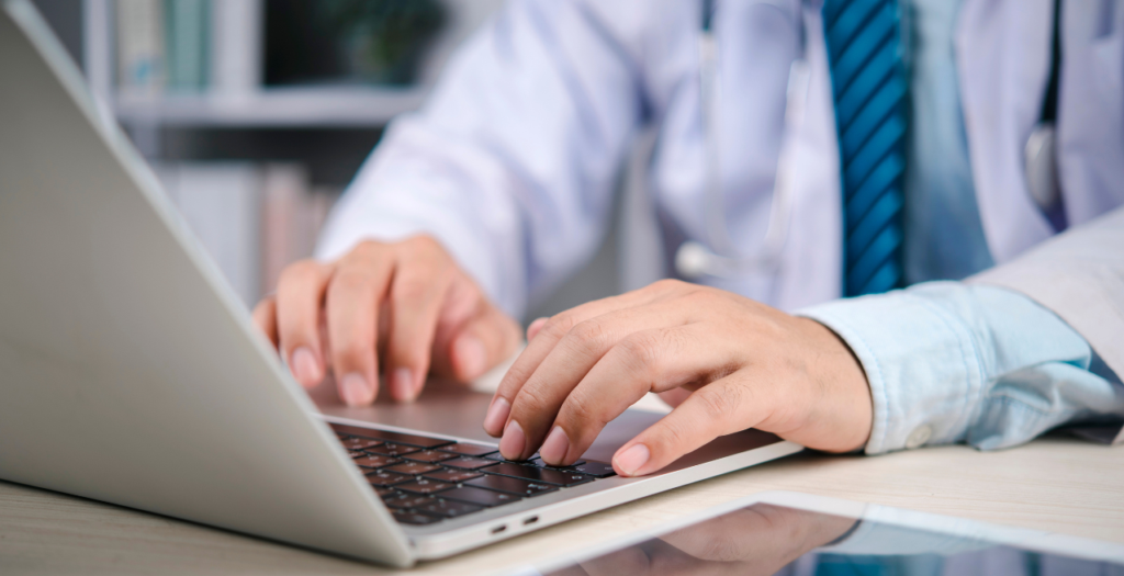 Provider with hands on laptop keyboard; he chose an ehr vs emr