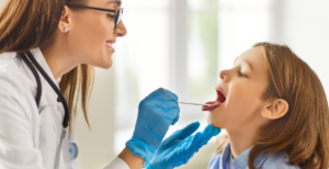 Provider looking at young girl's throat; her practice is part of a clinically integrated network