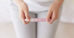 California IVF bill represented by woman holding pregnancy test in lap